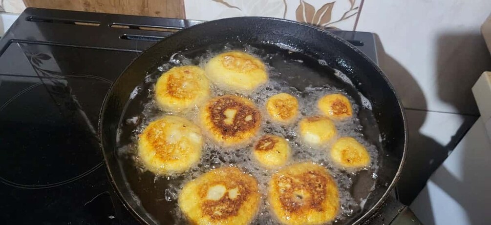 A frying pan with several golden-brown fried items. 4
