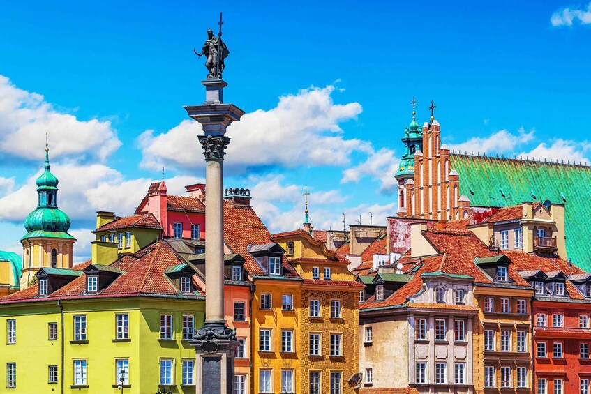 A colorful cityscape with a prominent statue in the foreground, a church with a green dome, and a variety of buildings with red-tiled roofs. 2
