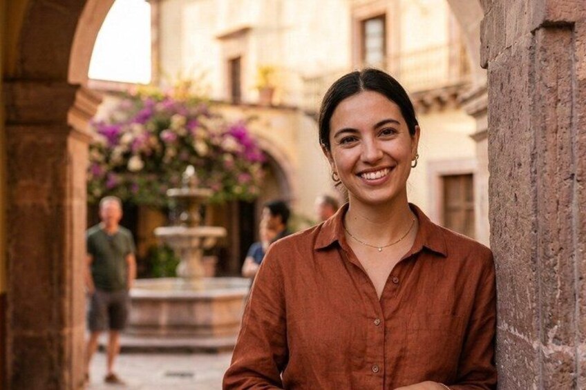 A person standing in an outdoor setting with a fountain and flowers in the background. 2