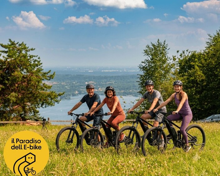 A group of cyclists on a grassy hill with a lake and cityscape in the background. 1