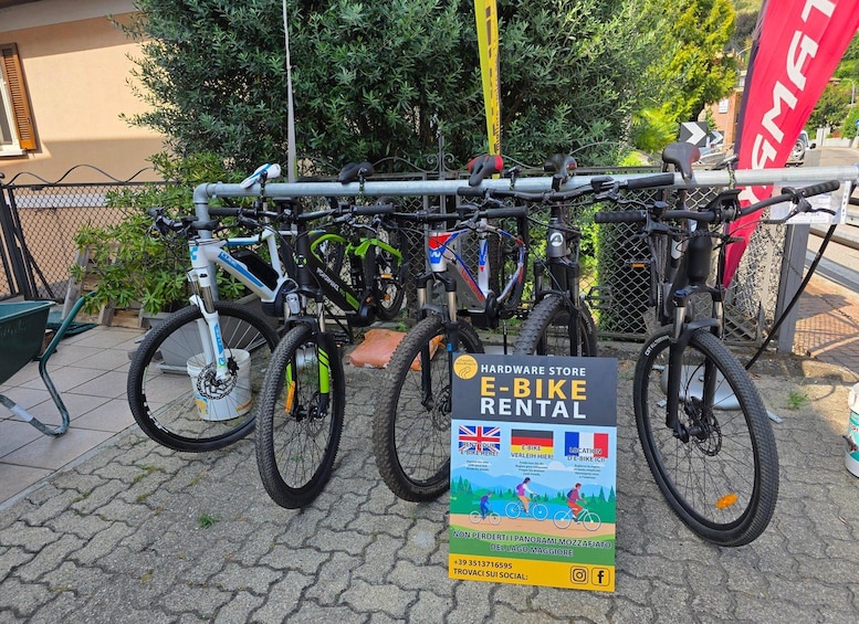 A sign for an e-bike rental service with multiple bicycles parked behind it. 3