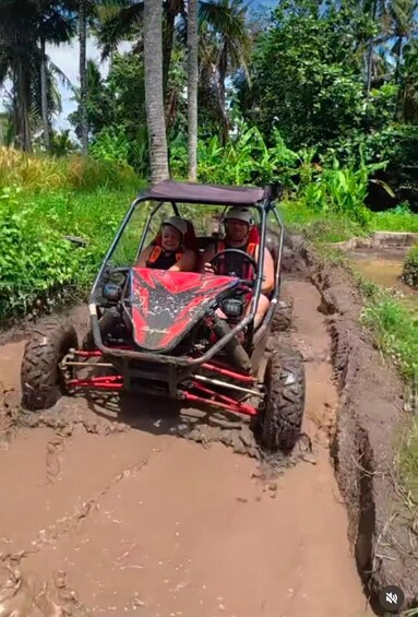 A red ATV navigating through a muddy path surrounded by greenery. 5