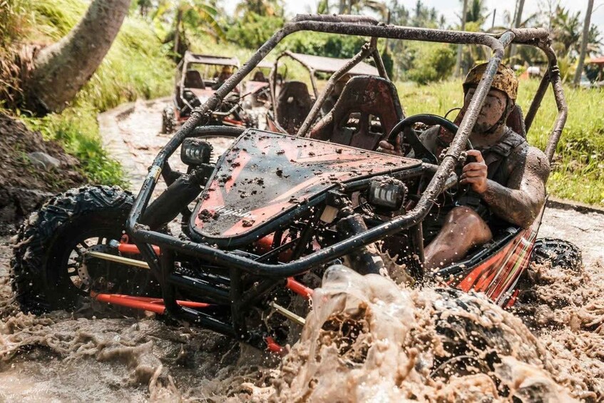A muddy off-road vehicle with a person driving, surrounded by water and mud splashes. 1