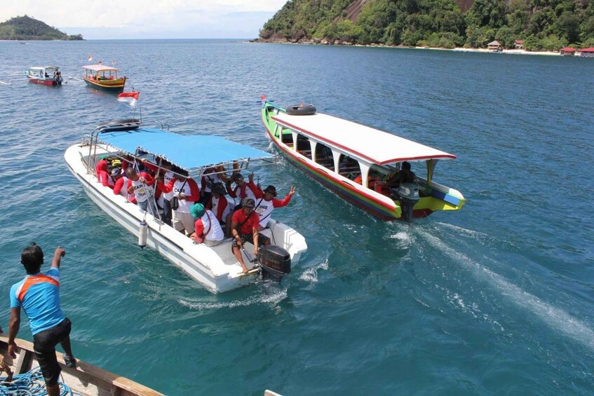 Un grupo de personas en un bote con una cubierta roja y blanca, otro bote con una cubierta verde y blanca, y una orilla con árboles y edificios. 2