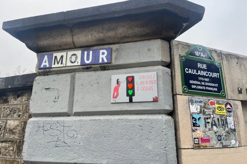 A street sign with 'AMOUR' and a traffic light. There's a plaque with a heart symbol and text. 4