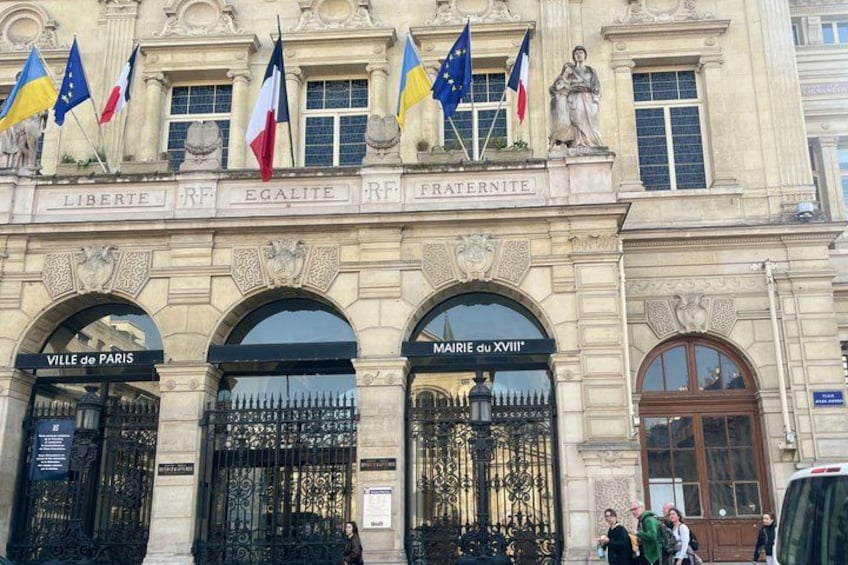 A historic building with ornate architecture, flags, and the names 'Ville de Paris' and 'MAIRIE du XVIIIe'. 3