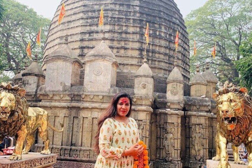 A person standing in front of a temple with a dome roof, flanked by golden lion statues. 1
