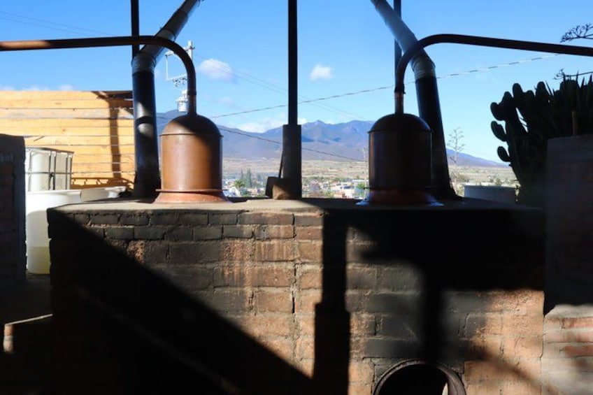 A rustic outdoor kitchen with brick walls, copper pots, and a view of mountains. 1