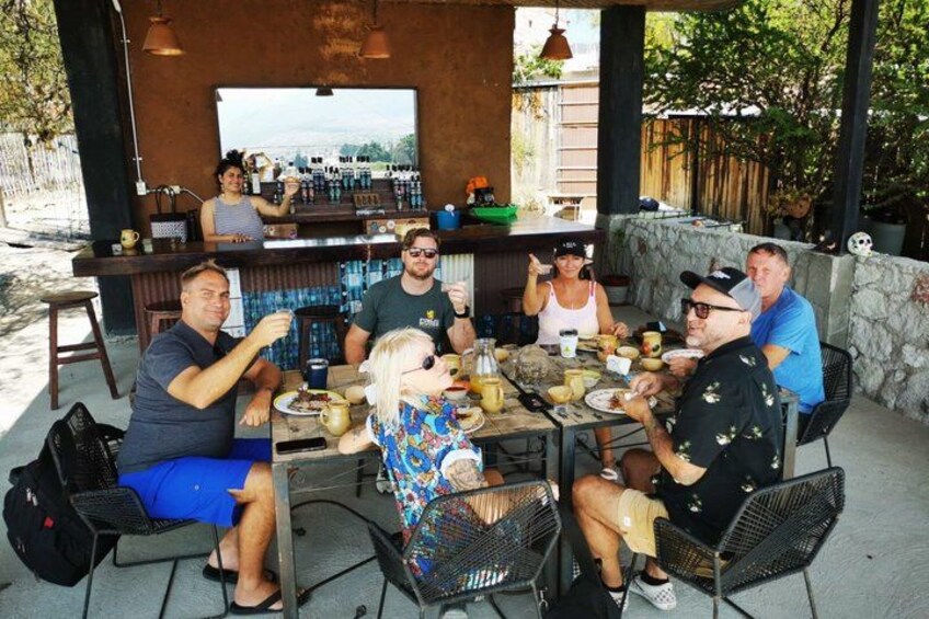 A group of people dining at an outdoor restaurant with a bar and a stone wall backdrop. 3