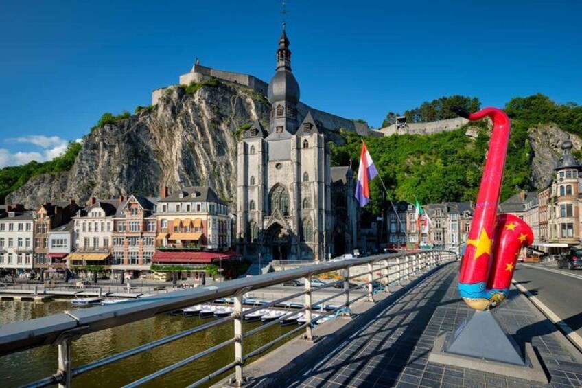 A bridge with a red sculpture, a church, and a castle on a hill. 1