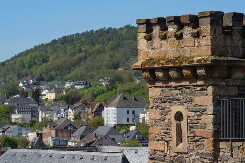 A stone tower, residential buildings, and a forested hill. 3