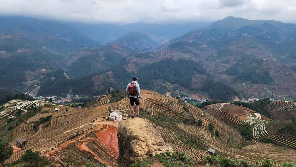 Un excursionista en la cresta de una montaña con vistas a campos cultivados en terrazas. 5