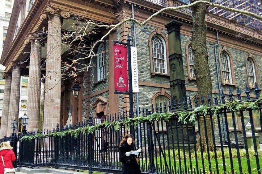 A historic building with columns, banners, and a black iron fence. 2