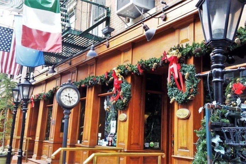 A building with wooden exterior, decorated with Christmas wreaths and garlands, a clock, and flags. 5
