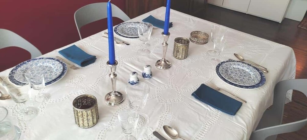 Mesa dispuesta para una comida con platos azules y blancos, cubiertos, servilletas azules y elementos decorativos como velas y cristalería. 2