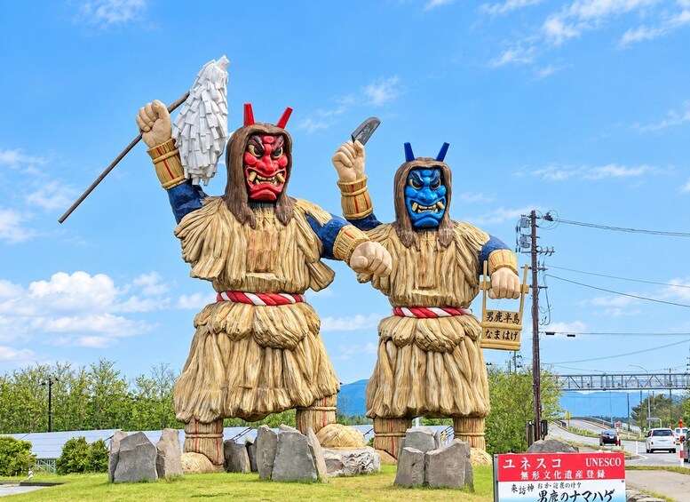 Two large statues of warriors with traditional attire and weapons, set against a clear sky. 1
