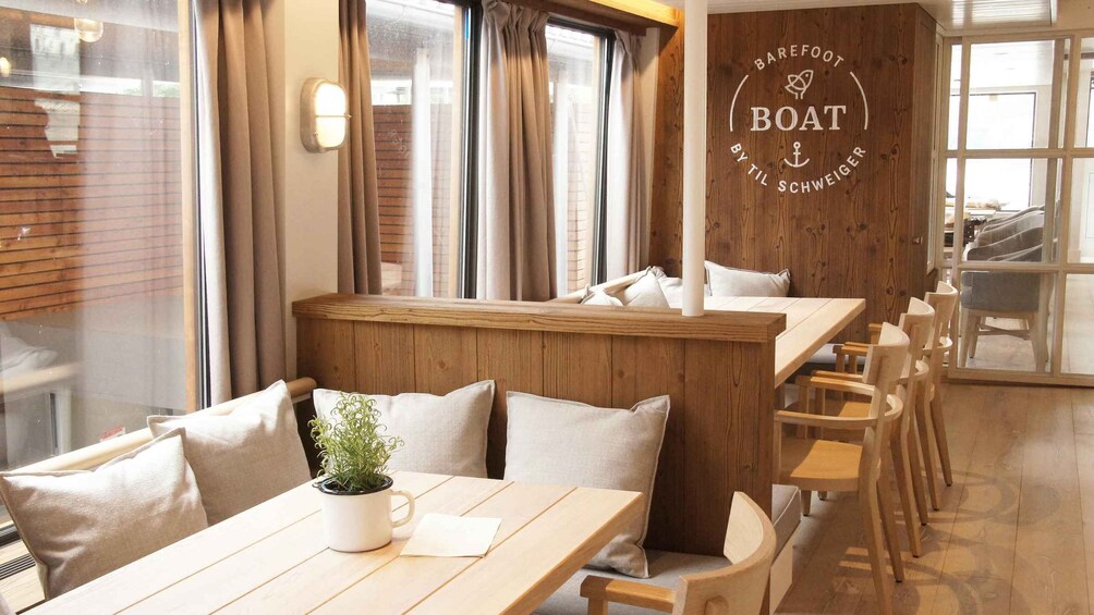 A cozy restaurant interior with wooden furniture, a plant on the table, and a sign on the wall. 3