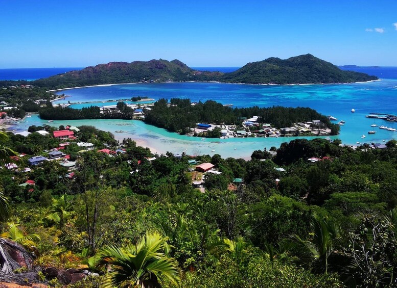 A coastal town with clear turquoise waters, lush greenery, and a small island with buildings. 1
