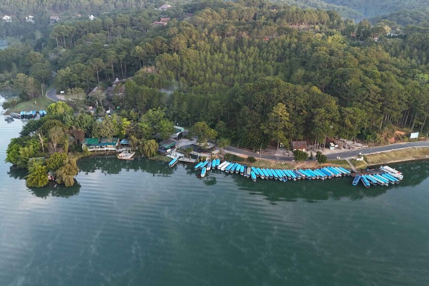 Un lago rodeado de bosque denso con un muelle lleno de barcos. 5