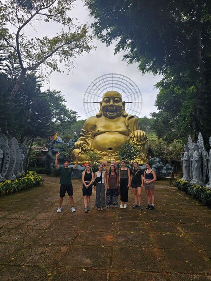 A large golden Buddha statue surrounded by trees and smaller statues. 3