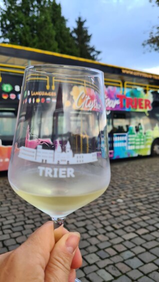 A hand holding a wine glass with a reflection of a colorful bus and a building in the background. 3