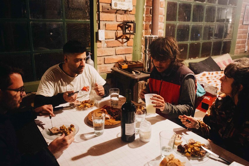 Een groep mensen dineert aan een tafel vol verschillende gerechten en drankjes. 3