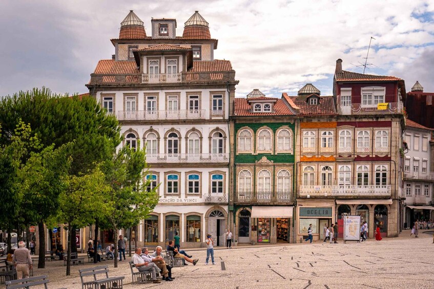 Una plaza histórica europea con edificios ornamentados, adoquinado y gente sentada en bancas. 5