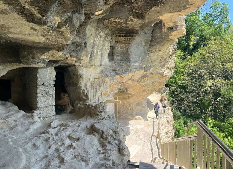 A rocky cliff with a cave entrance and a wooden staircase leading up. 1