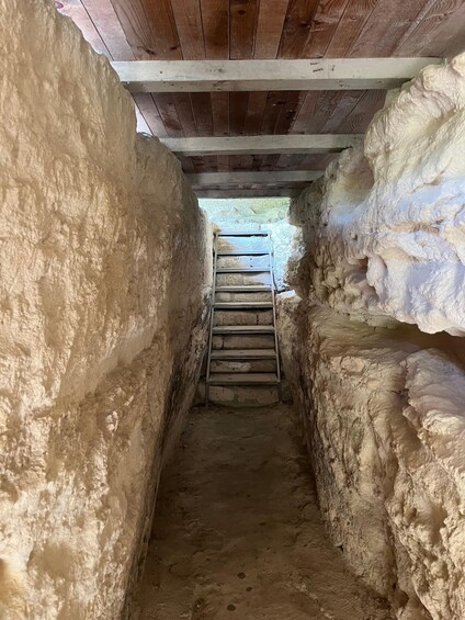 A narrow stone passageway with a wooden staircase leading upwards. 3