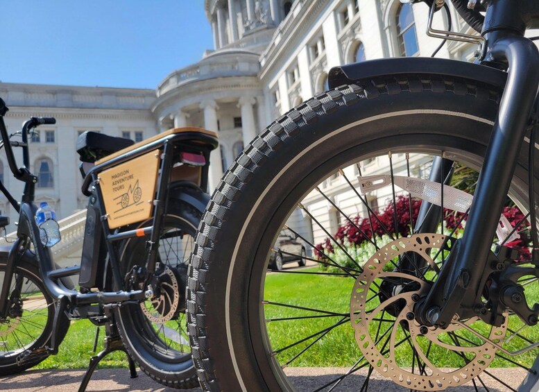 A bicycle with a 'Madison Adventure Tours' sign, a large front tire, and a disc brake. 5