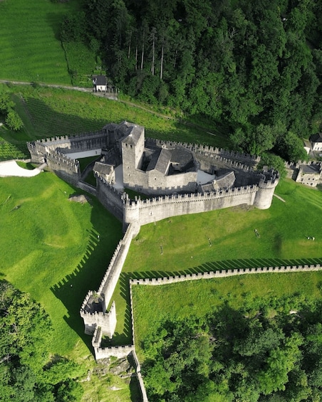 An aerial view of a medieval castle surrounded by lush green fields and dense forests. 2