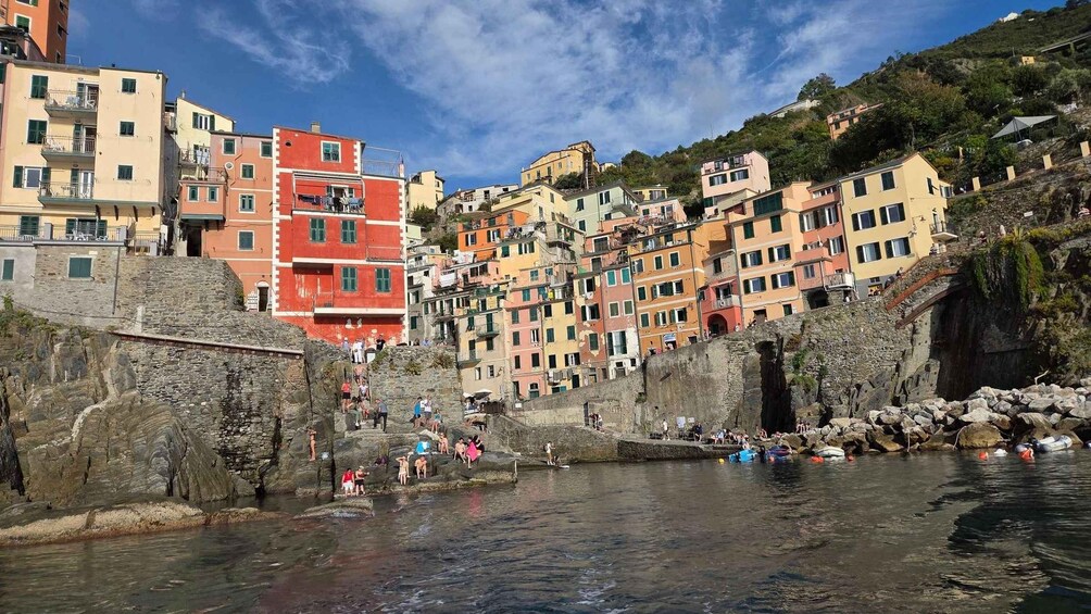 A coastal town with colorful buildings, a rocky shoreline, and people engaging in water activities. 3