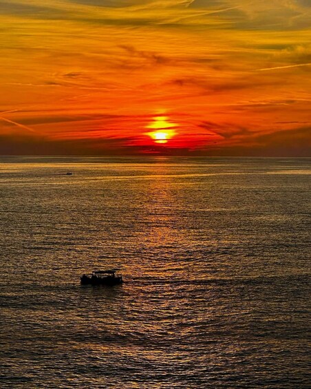 A sunset over a calm sea with a boat in the foreground. 1