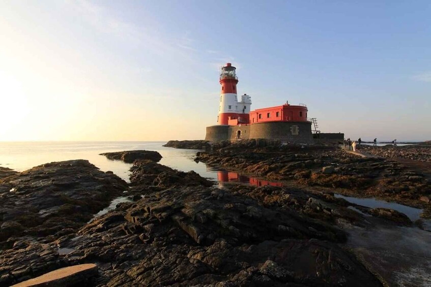 A lighthouse on a rocky shore with calm water in the background. 5