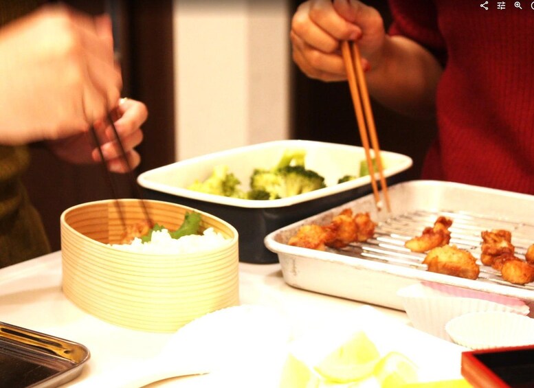 A dining table with a bowl of rice, a tray of grilled food, and a plate of broccoli. 3