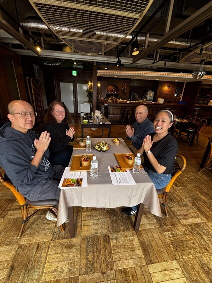 A group of people seated at a table in a restaurant with a wooden floor and a high ceiling. 5