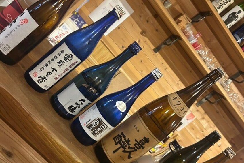 Bottles of sake on wooden shelves. 1
