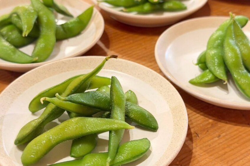 Three plates of green edamame on a wooden table. 2