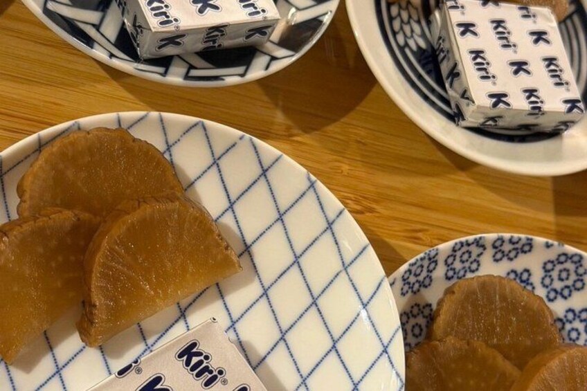 A plate with several pieces of food, a bowl with packaged items, and a patterned plate on a wooden table. 4
