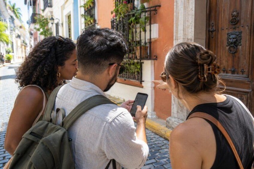 Three people standing on a cobblestone street, one holding a smartphone. 5