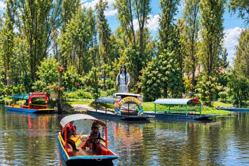 A river with boats, a statue, and a garden. 5
