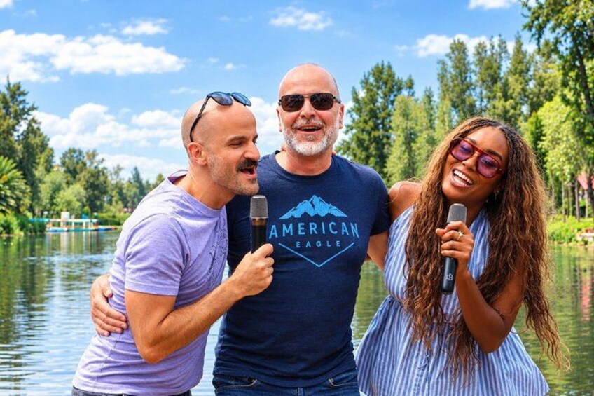 Three people standing by a lake with trees in the background. 1