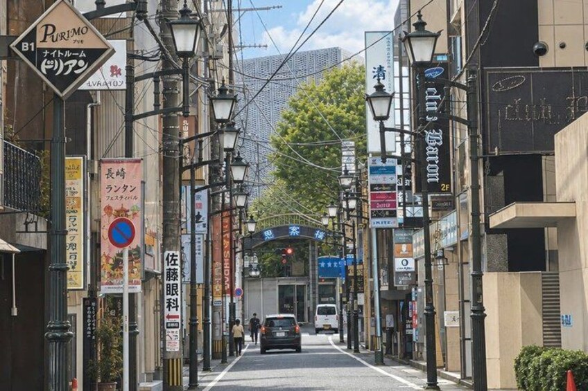 A street lined with shops and signs, a car driving down the road, and a building with a sign that reads 'Bar'. 4