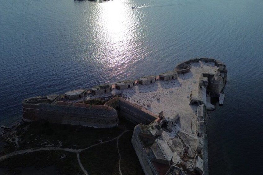 An aerial view of a historical fortification by the water with a moat and walls. 4