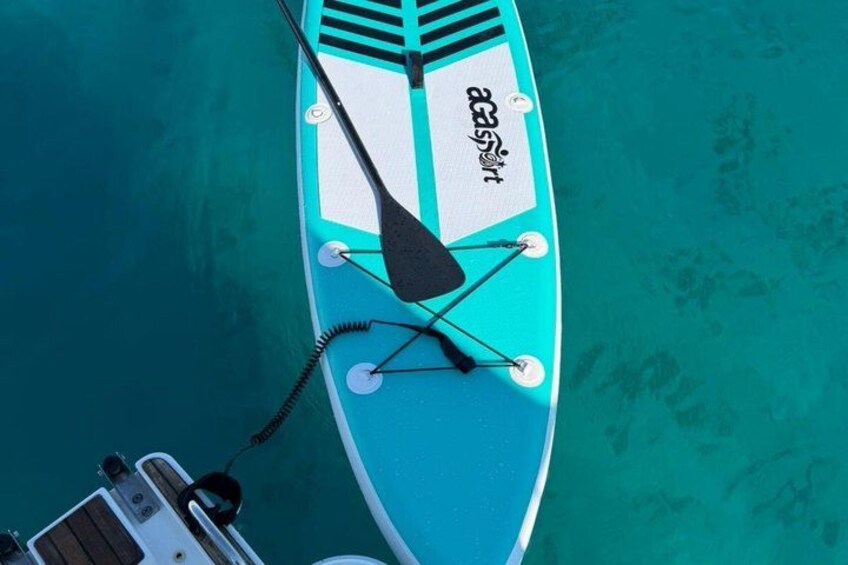 A blue paddleboard with a black paddle and a rope attached to a boat. 5
