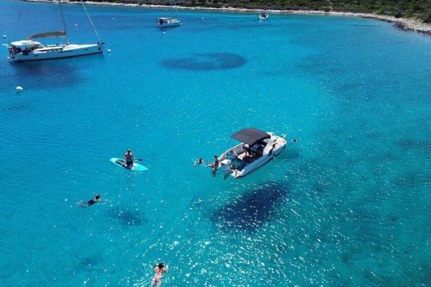 A clear blue sea with boats and people. 1