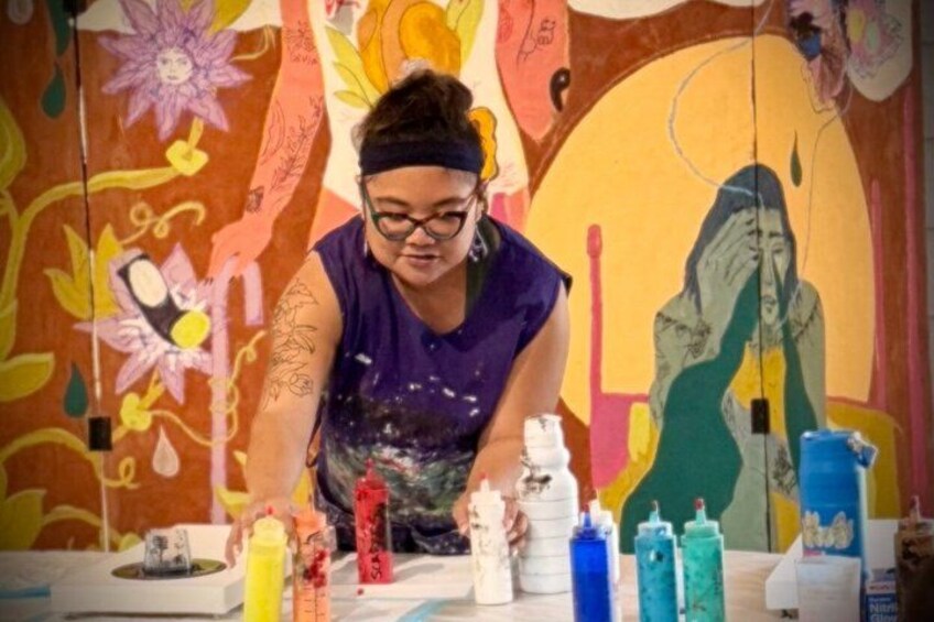 A person painting a mural with colorful paints on a wall. 1
