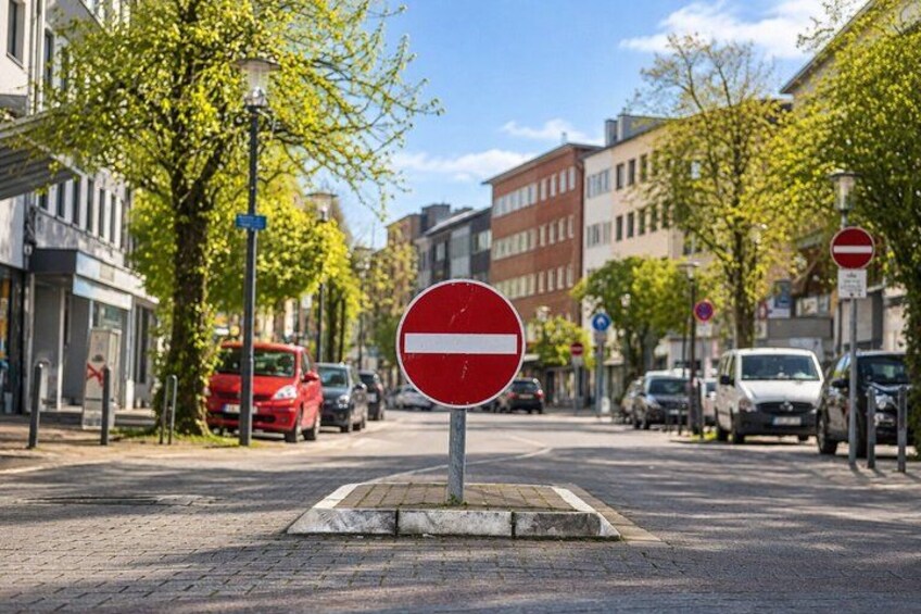 A street with a no entry sign, parked cars, and buildings. 4