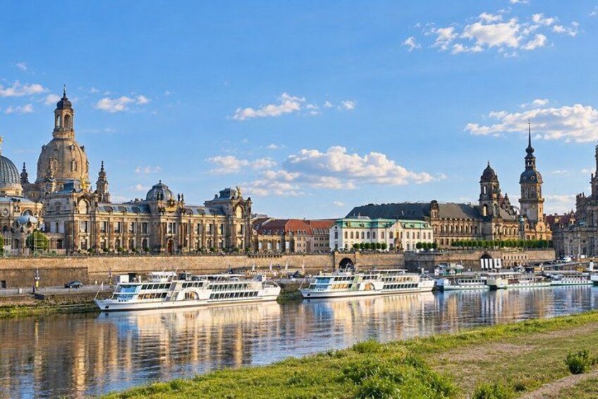 A river with boats, a large historic building with domes, and a clear sky. 4