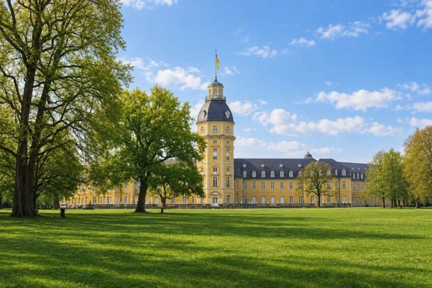 A large yellow building with a tower, surrounded by green grass and trees. 4